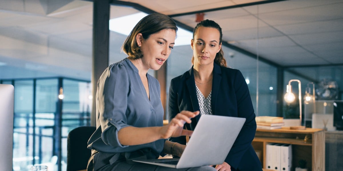 two professional women in the office looking at a laptop