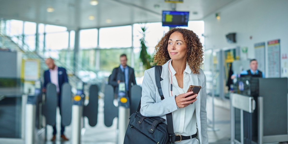 professional woman, traveler, in airport, holding cellphone in hand