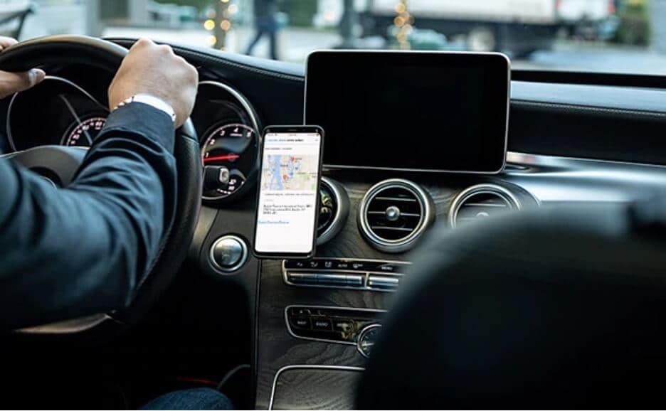 Person driving car with Concur Drive on smartphone