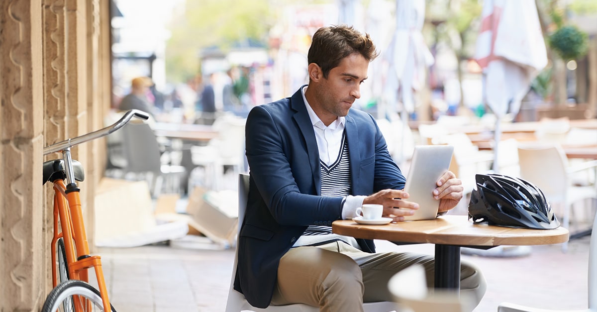 man working on laptop sitting at a cafe table