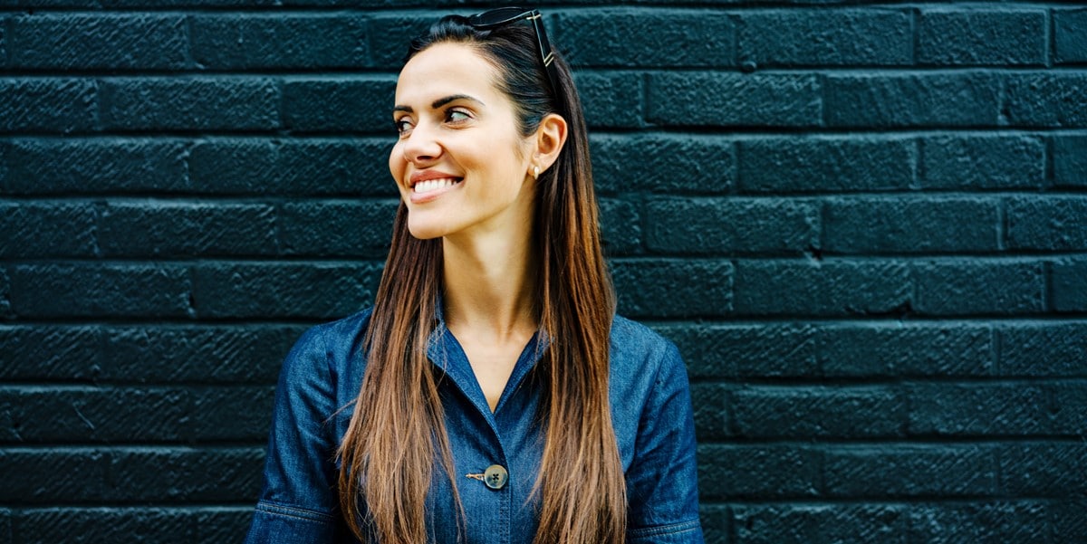 woman in front of blue wall, smiling