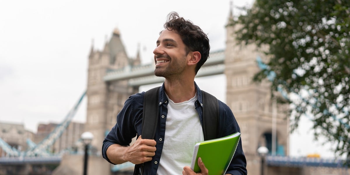 man walking through city with backpack and notebook