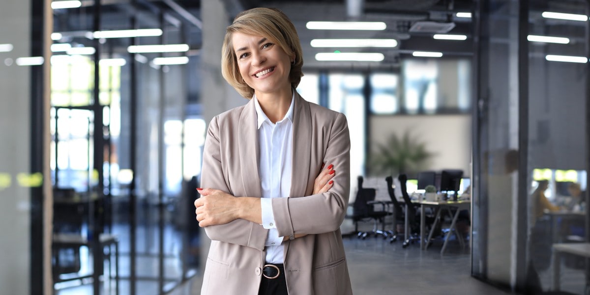 businesswoman smiling, arms crossed, in the office