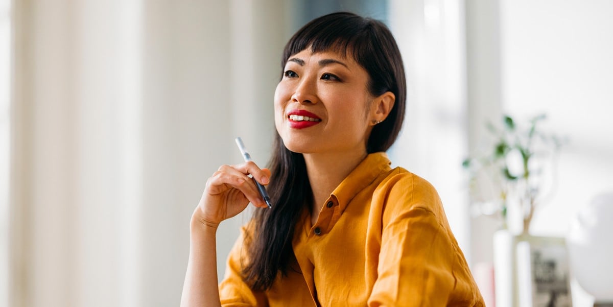 woman smiling, holding a pen