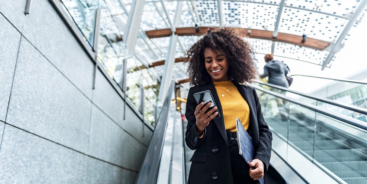 woman traveler using escalator, looking at phone in hand