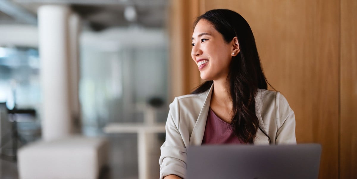 professional woman smiling in office using laptop