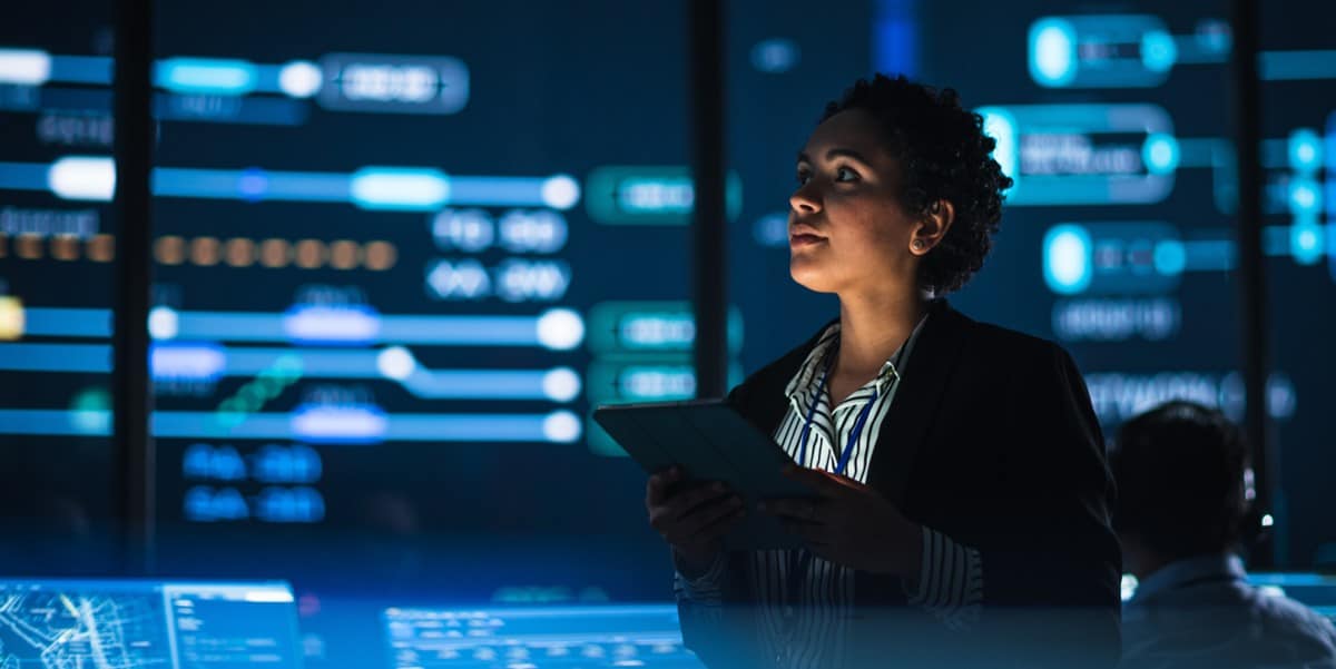 professional woman sitting in office, lit up screen behind her