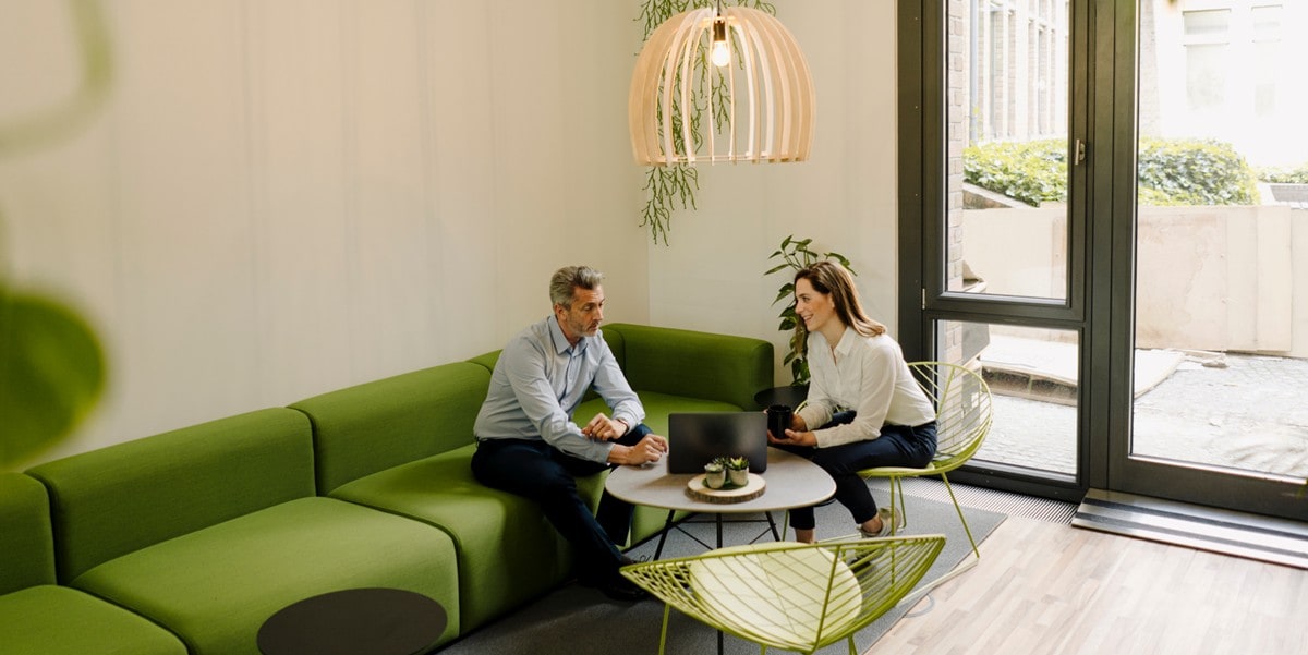 two people seated on a green sofa