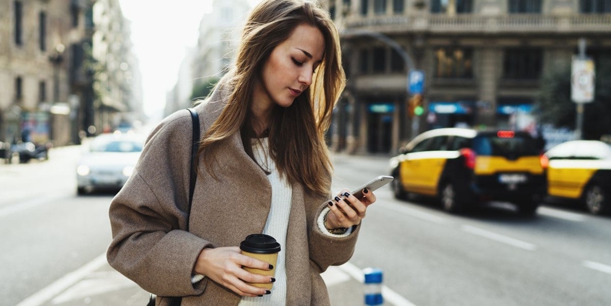 traveler in city, looking at phone in hand