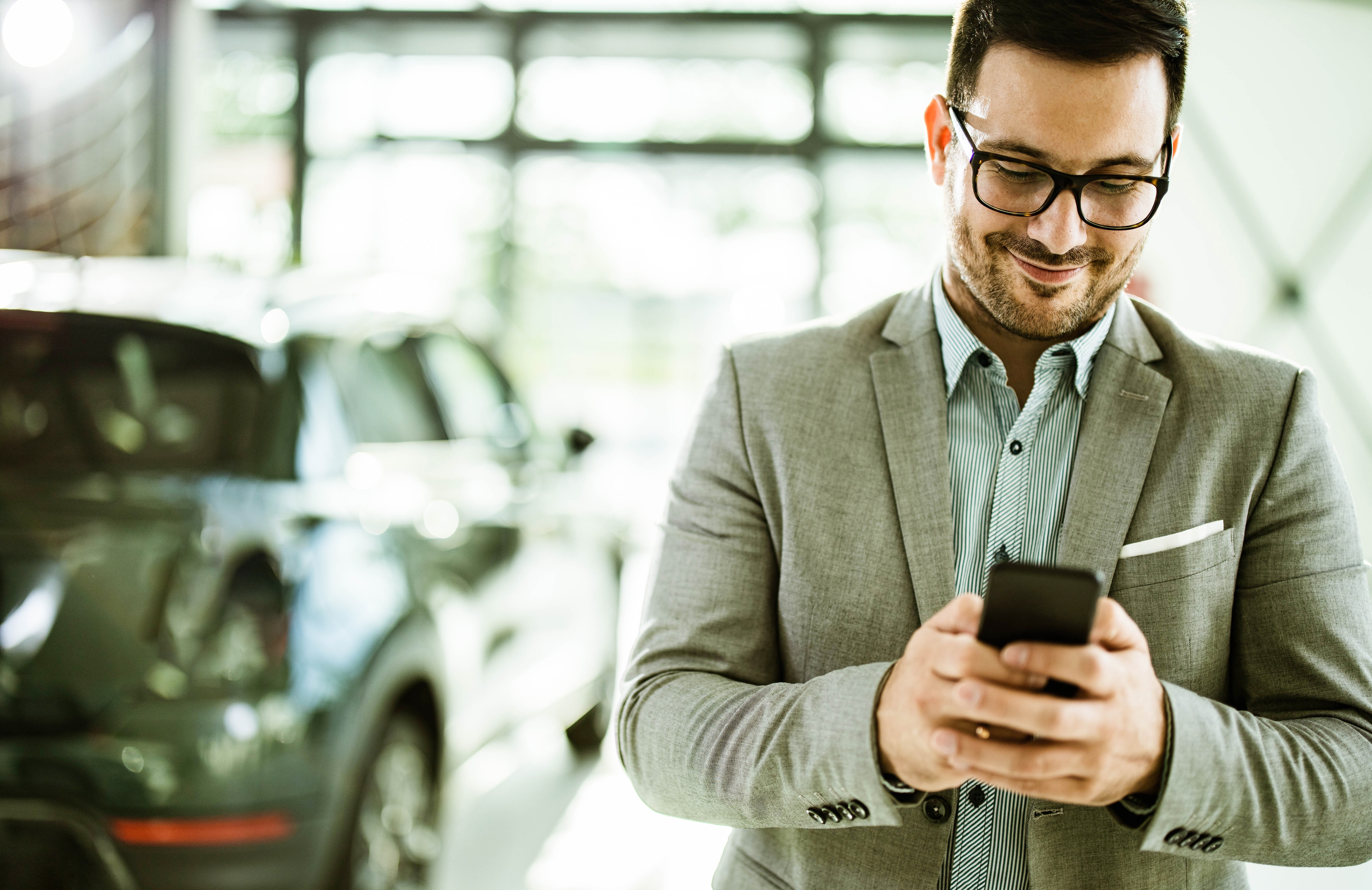 man looking at phone with rental car