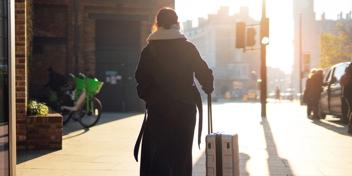 person walking through city with suitcase