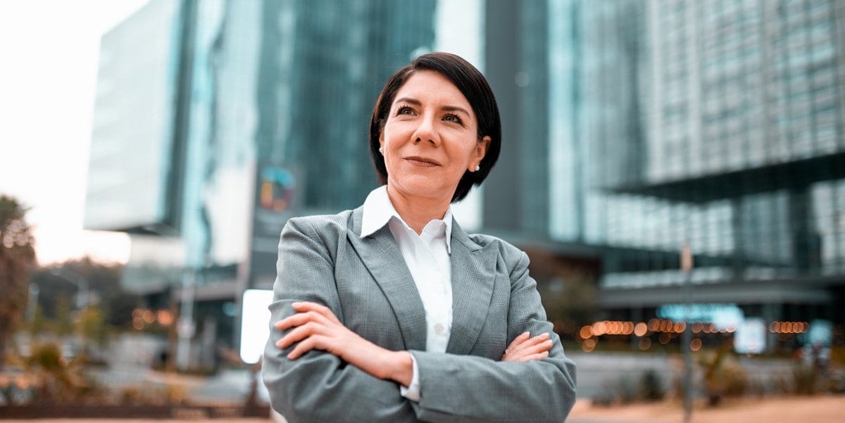 professional woman smiling, standing outside of buildings