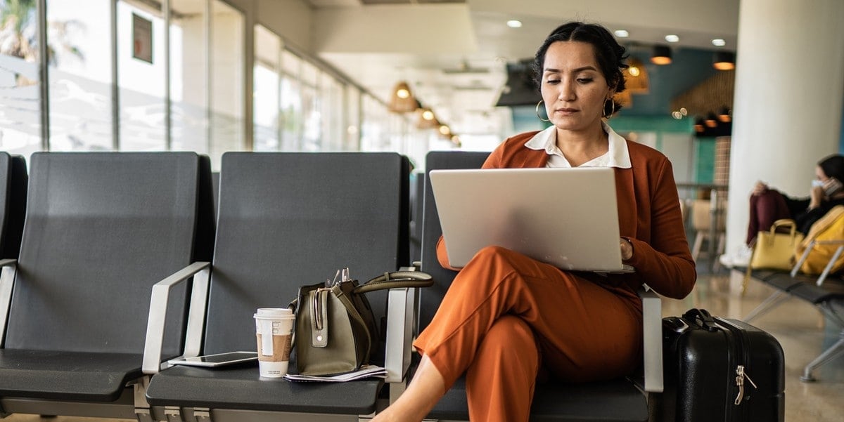 professional woman working in an airport lounge, using laptop