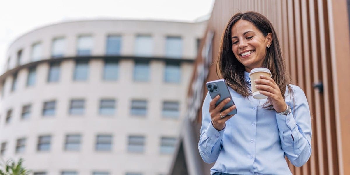 woman standing outside building, looking at phone in  hand
