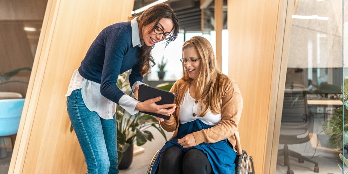 two people in office, looking at tablet