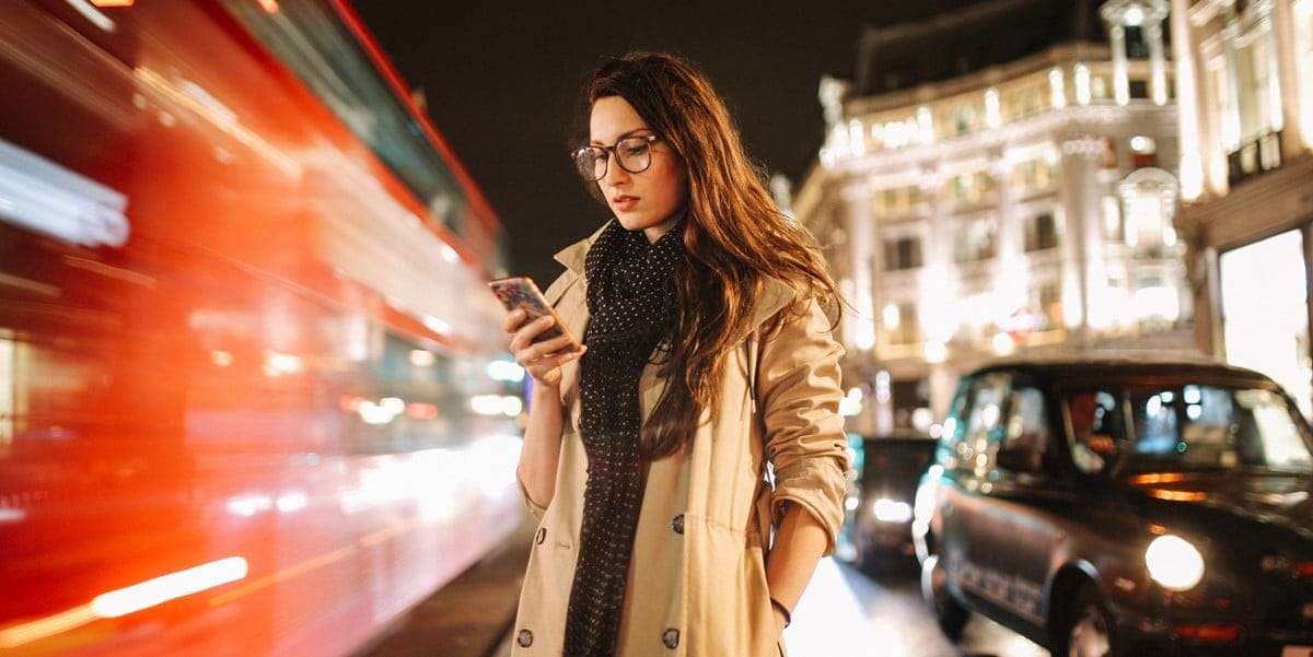 woman in a city, looking down at cell phone