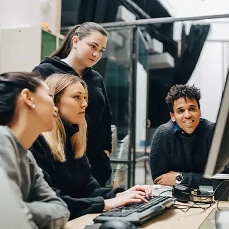 people working around a desktop computer
